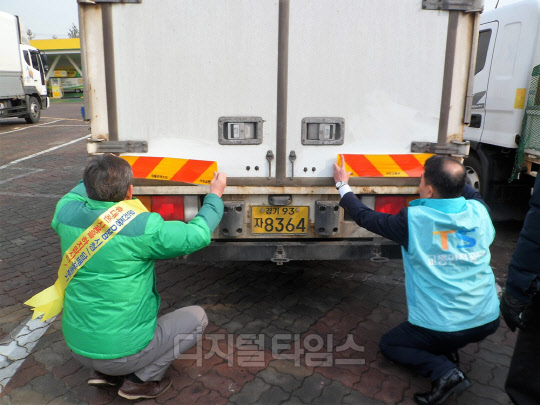 교통안전공단 경기북부지사 직원들이 26일 경기 파주출판도시 휴게소에 주차된 화물 차량에 후부반사판을 부착하고 있다.<교통안전공단 경기북부지사 제공>